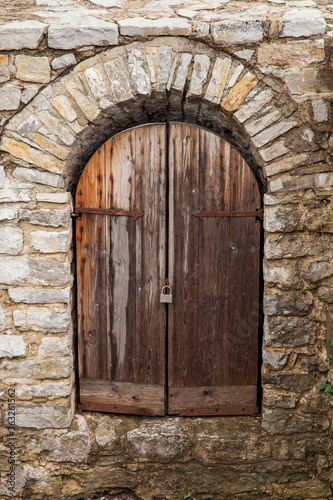 The gate of the medieval castle, the wooden gate doors in the stone walls. Ancient defensive structure, fort.