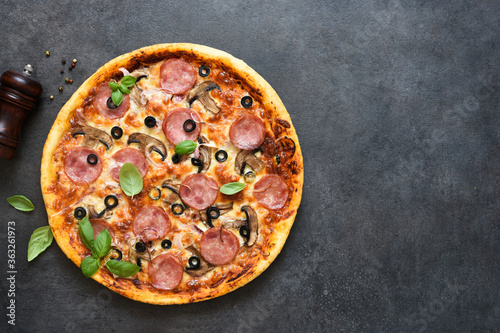 Pizza with salami, mushrooms and tomato sauce on a black background. View from above.