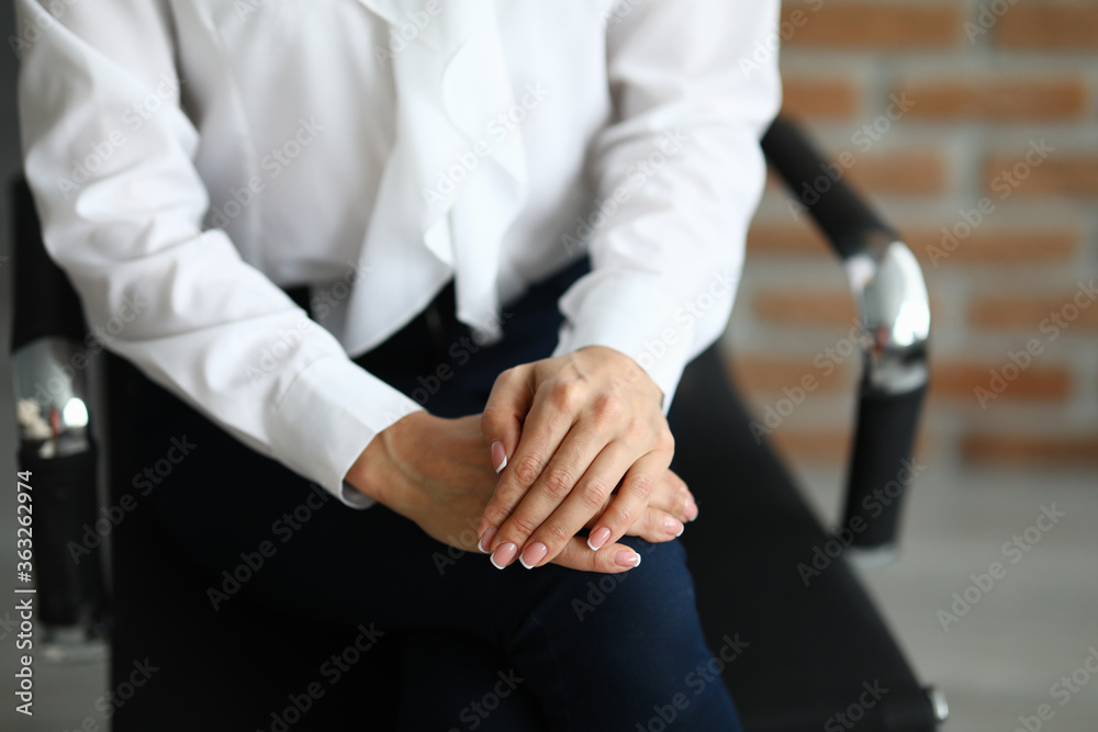 Woman sits on chair with hands clasped. Courses on personal growth and self control and self confidence