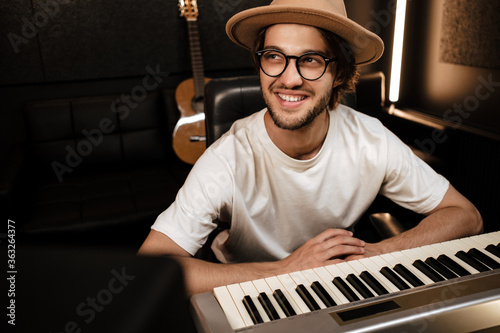 Billede på lærred Young attractive stylish musician happily working in modern recording studio
