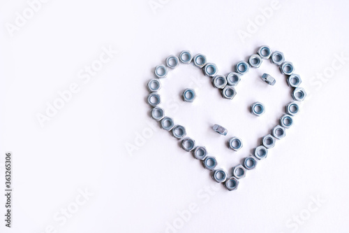 Heart laid out of bolts, nuts on a white background. Father's Day and wedding anniversary concept.