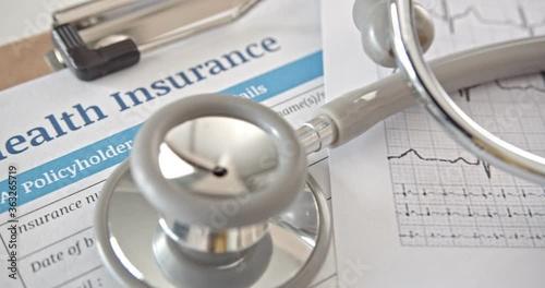 Health insurance form on a table in a doctor or physician office. Stethoscope on an insurance agreement, paper that has a plan or policy covers or insure the risk of a person incurring medical expense