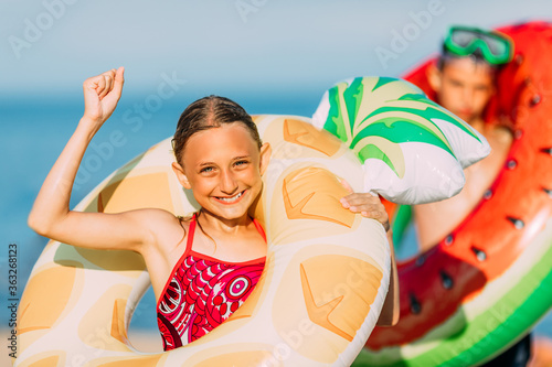 Happy kids little boy and girl have fun on the beach with inflatable swimming circles, celebrate the victory.Travel, summer vacation
