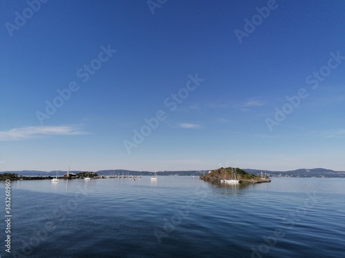 Small boats and an island on the lake on a beautiful summer day © Kristoffer