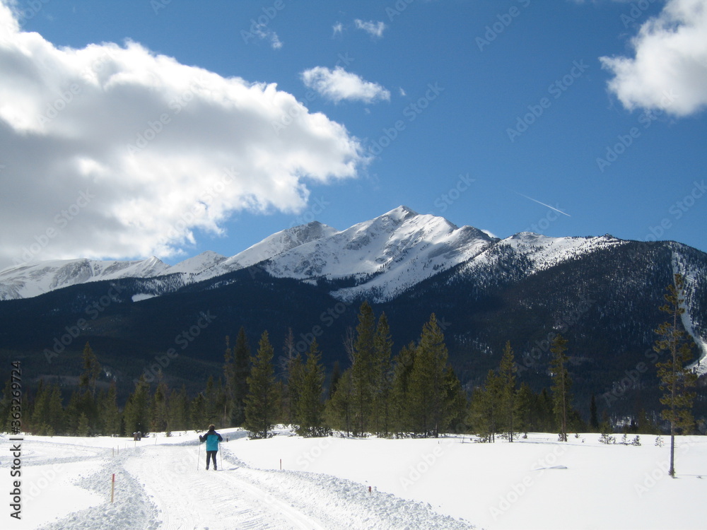 Cross Country Skier with Snowy Peak Blue Sky Background