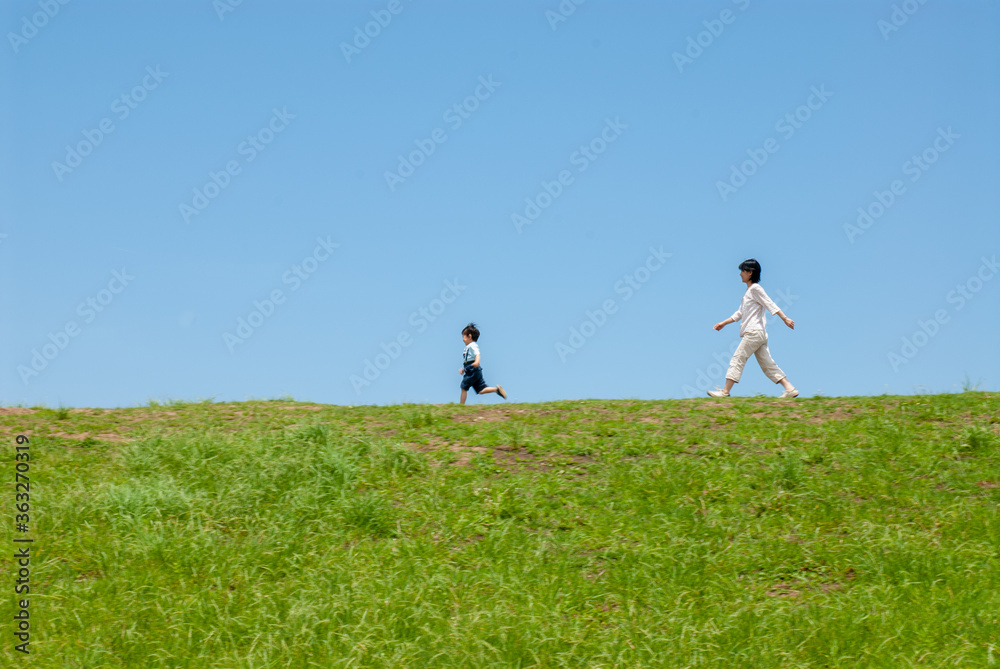 丘の上で遊ぶ親子（母親と子ども）