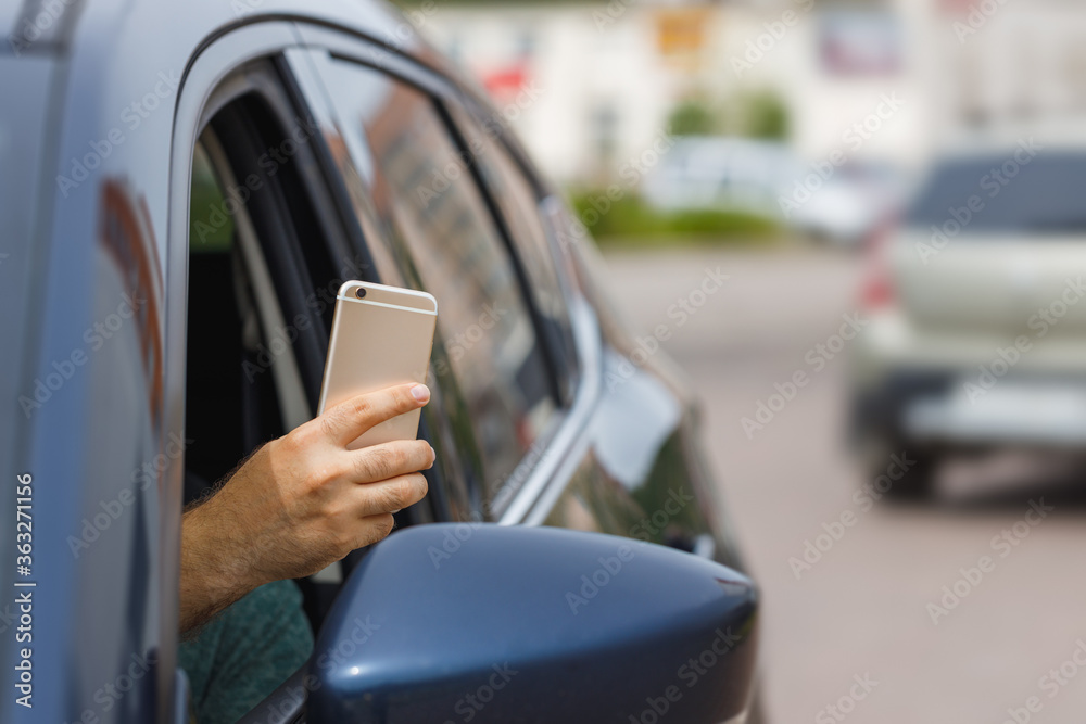 Man uses mobile phone to take a photo from a car window. Man uses mobile phone to take a photo from a car window.