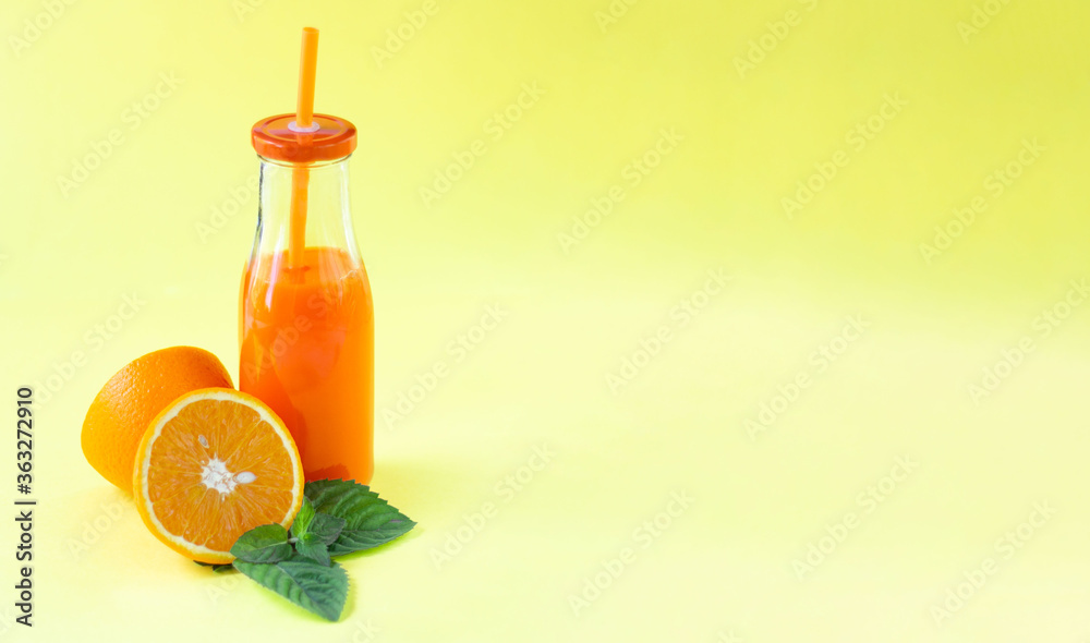 Minimalistic composition. Bright, juicy image. Fresh citrus juice with mint in a glass bottle with a tube. Yellow background. Empty space for text Minimalistic composition. Bright, juicy image. Fresh citrus juice with mint in a glass bottle with a tube. Yellow background. Empty space for text