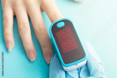 Health and medicine. Monitoring oxygen saturation of blood with a special device on a blue background