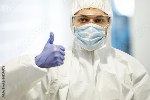 corona virus concept. male scientist doctor in mask, glasses and protective suit showing thumb up and getting ready for COVID-19 pandemic outbreak quarantine