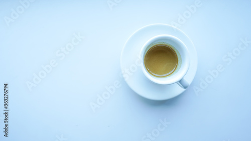 white cup and plate fill with coffee espresso on white table beside window light cool tone top view right side stock photo