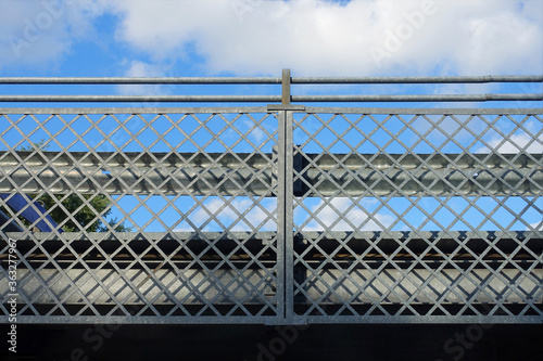 Detail of parking garage, metal fence texture with blue sky as background.