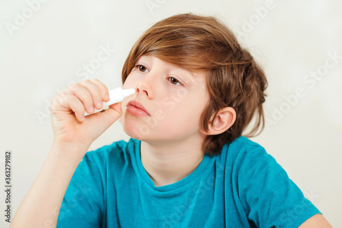 Sick kid with runny nose using nasal medicine spray. Nasal allergy.