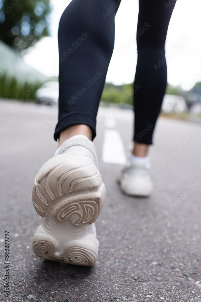 selective focus of white sneakers of sportswoman exercising on asphalt selective focus of white sneakers of sportswoman exercising on asphalt