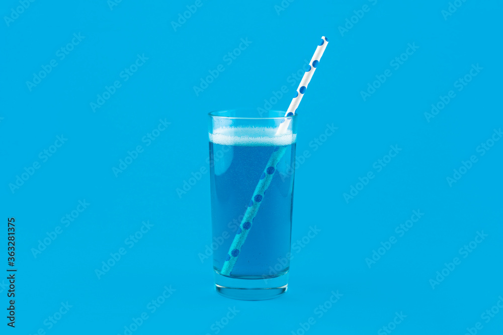 Blue lemonade with gas bubbles and a cocktail straw isolated on blue background Blue lemonade with gas bubbles and a cocktail straw isolated on blue background