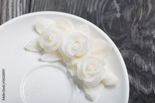 Handmade saucer decorated with polymer clay roses. Jewelry made of white polymer clay. Close up shot 