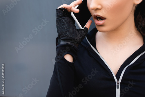 cropped view of young sportswoman talking on smartphone