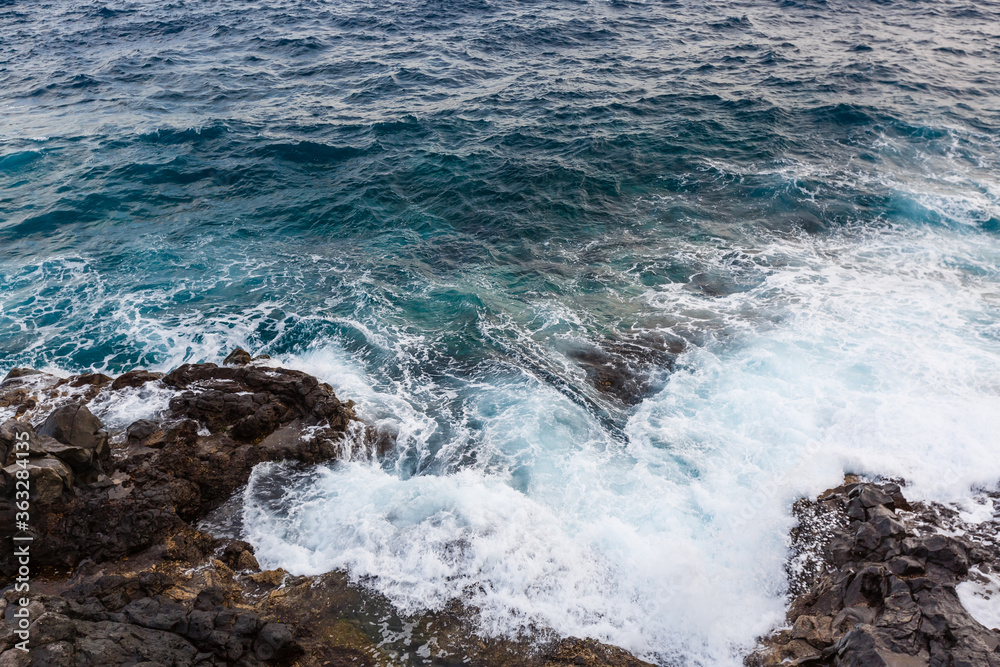 ocean waves hit and crash against stones