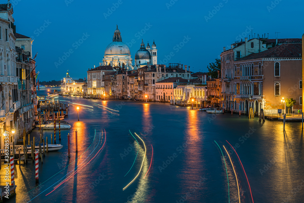 View of Basilica di Santa Maria della Salute and grand canal from Accademia Bridge at night in Venice, Italy.