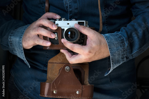 Men in jeans shirt holding an old rangefinder film camera camera © Ivan