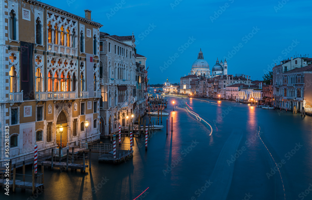 View of Basilica di Santa Maria della Salute and grand canal from Accademia Bridge at night in Venice, Italy.