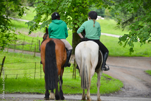 Two females enjoy riding out in the English countryside on their beautiful horses on a sunny day relaxing and chatting as they enjoy riding their horses.