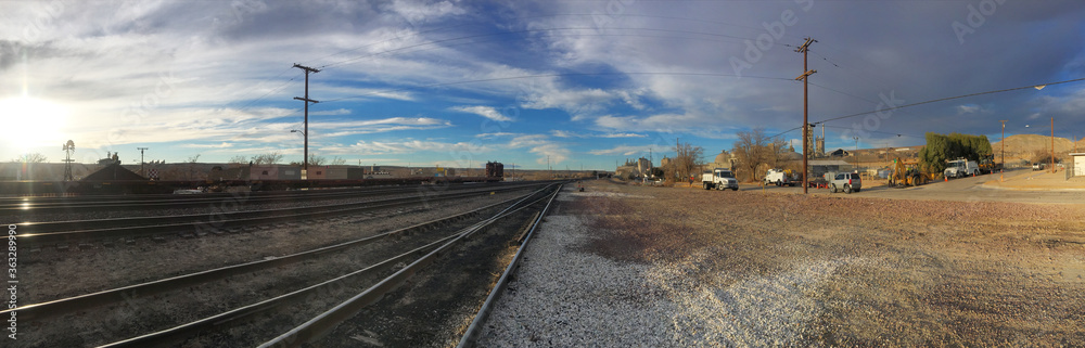 Panorama view of beautiful sunset sky over railroad tracks & side road in California suburb
