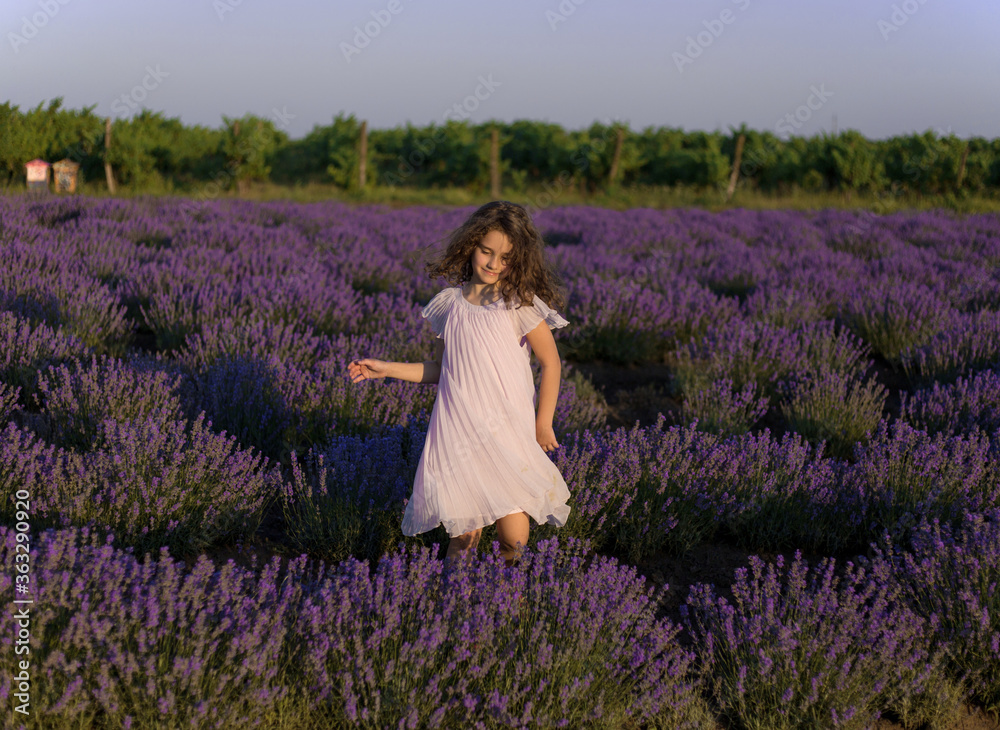 Cheerful pretty little girl in pink dress in a lavender field at the sunset background. Cheerful pretty little girl in pink dress in a lavender field at the sunset background.