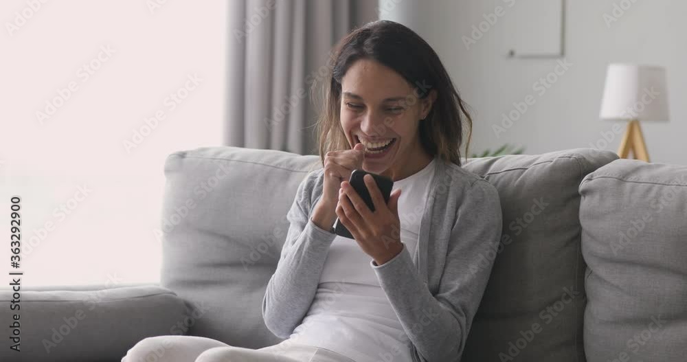 Happy overjoyed girl holding phone celebrate good mobile news surprise bid win game app victory sit on sofa at home, excited young woman winner screaming yes rejoicing success looking at cellphone Happy overjoyed girl holding phone celebrate good mobile news surprise bid win game app victory sit on sofa at home, excited young woman winner screaming yes rejoicing success looking at cellphone