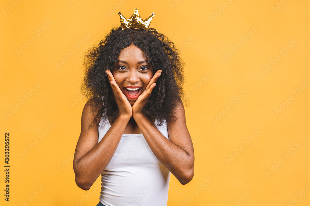 Young african american woman wearing golden crown of queen over isolated over yellow background with a happy and cool smile on face. Lucky person. Young african american woman wearing golden crown of queen over isolated over yellow background with a happy and cool smile on face. Lucky person.