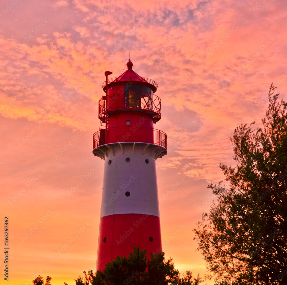 A small and beautiful lighthouse in the evening dawn sunset with pink clouds and bright light in Falshöft, Germany