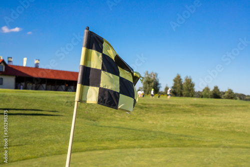 A checkered flag on a golf course signifying a hole against gold building