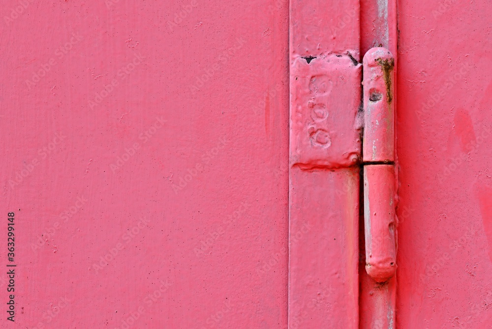 Red steel gate with a large metal hinge. Rusty metal background. The texture of the metal. Red steel gate with a large metal hinge. Rusty metal background. The texture of the metal.