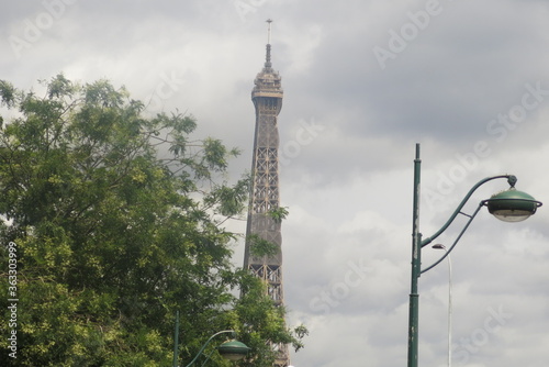 Haut de la tour Eiffel a coté d'un arbre et d'un lampadaire