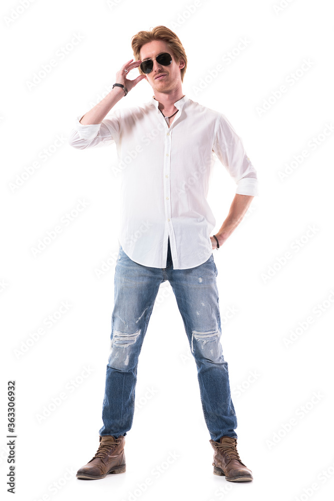 Cool self assured young handsome man holding sunglasses and posing at camera. Full body length isolated on white background. Cool self assured young handsome man holding sunglasses and posing at camera. Full body length isolated on white background.