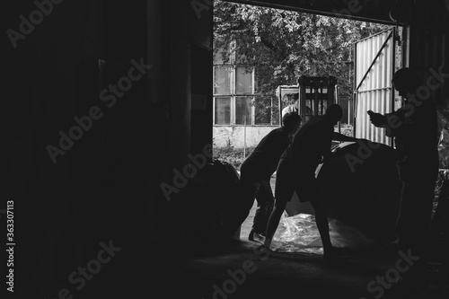 Workers, loader. Hard work. Acceptance of goods at the warehouse. industry, paper mill. The concept of low-paid, harmful work. Place for text. Black and white. copy space