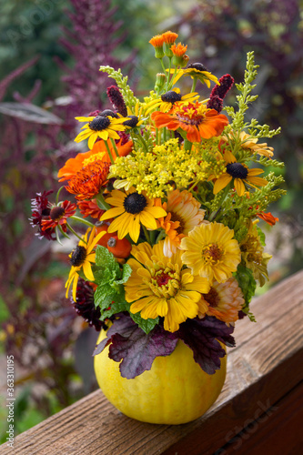 Vertical image of a fresh fall (autumn) arrangement of garden flowers in a hollowed-out gourd