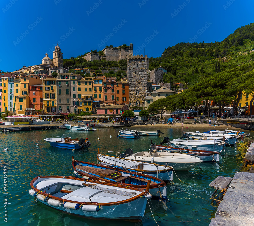 Small fishing boats moored in front of the colourful buildings of the old town of Porto Venere, Italy in the summertime