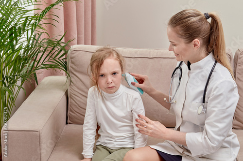Frightened girl sitting on the couch. Doctor checks the hearing of the child.