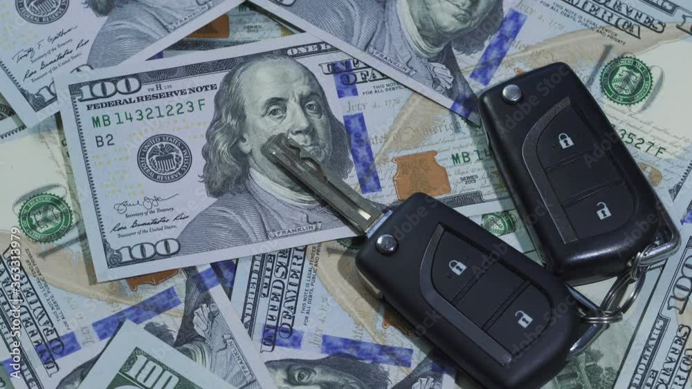 Close-up of car keys on stack of hundred dollar bills rotating. Buying car concepts. Close-up of car keys on stack of hundred dollar bills rotating. Buying car concepts.