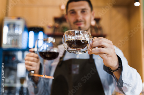 Syphon alternative method of making coffee. Barista gives hot coffee in double glass cup to customers. Coffee brewing in cafe. Scandinavian method of coffee making.
