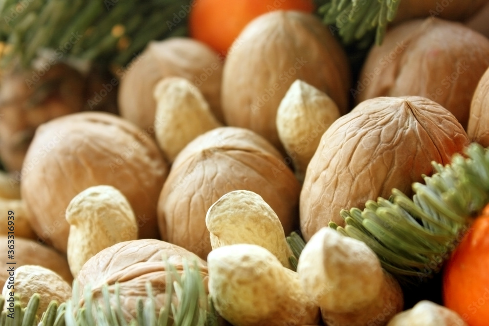 Assorted peanuts, walnuts. Between them is spruce branch, orange. Gift bouquet of nuts. Christmas and New Year theme. It holiday theme. Food. Background. Macro. Electoral focus. Copying space for text Assorted peanuts, walnuts. Between them is spruce branch, orange. Gift bouquet of nuts. Christmas and New Year theme. It holiday theme. Food. Background. Macro. Electoral focus. Copying space for text