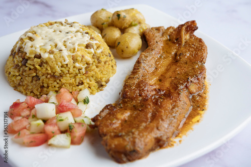 Rice with lentils, baked pork ribs, boiled potatoes, and tomato cucumber salad. Arroz moro.