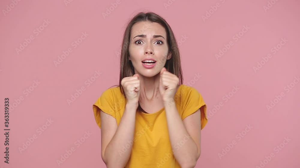 Young woman girl 20s years old in yellow t-shirt posing isolated on pastel pink background studio. People lifestyle concept. Waiting for special moment worried making wish doing winner gesture say Yes Young woman girl 20s years old in yellow t-shirt posing isolated on pastel pink background studio. People lifestyle concept. Waiting for special moment worried making wish doing winner gesture say Yes