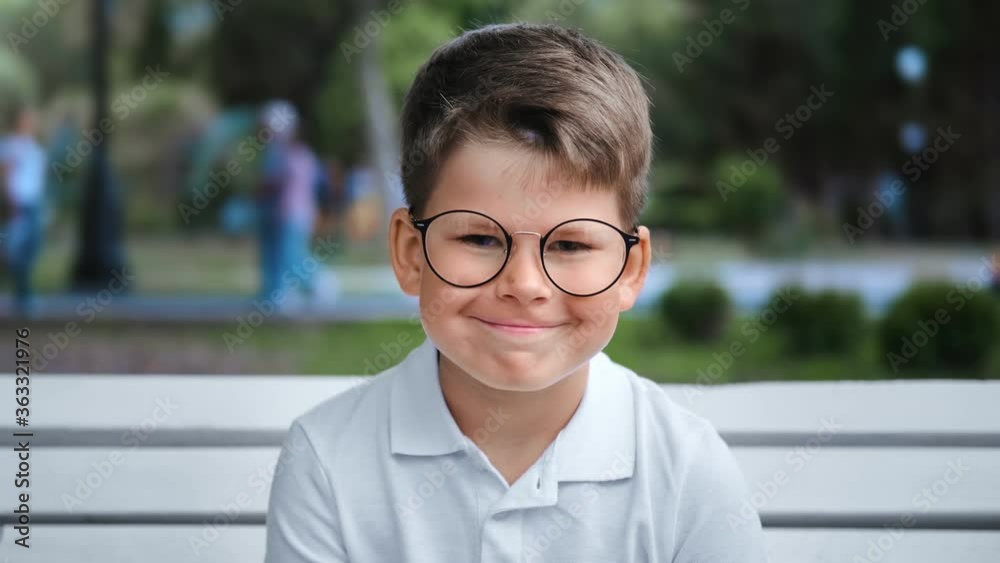 Portrait of smiling cute boy posing on bench at city park. Medium close up shot on 4k RED camera Portrait of smiling cute boy posing on bench at city park. Medium close up shot on 4k RED camera