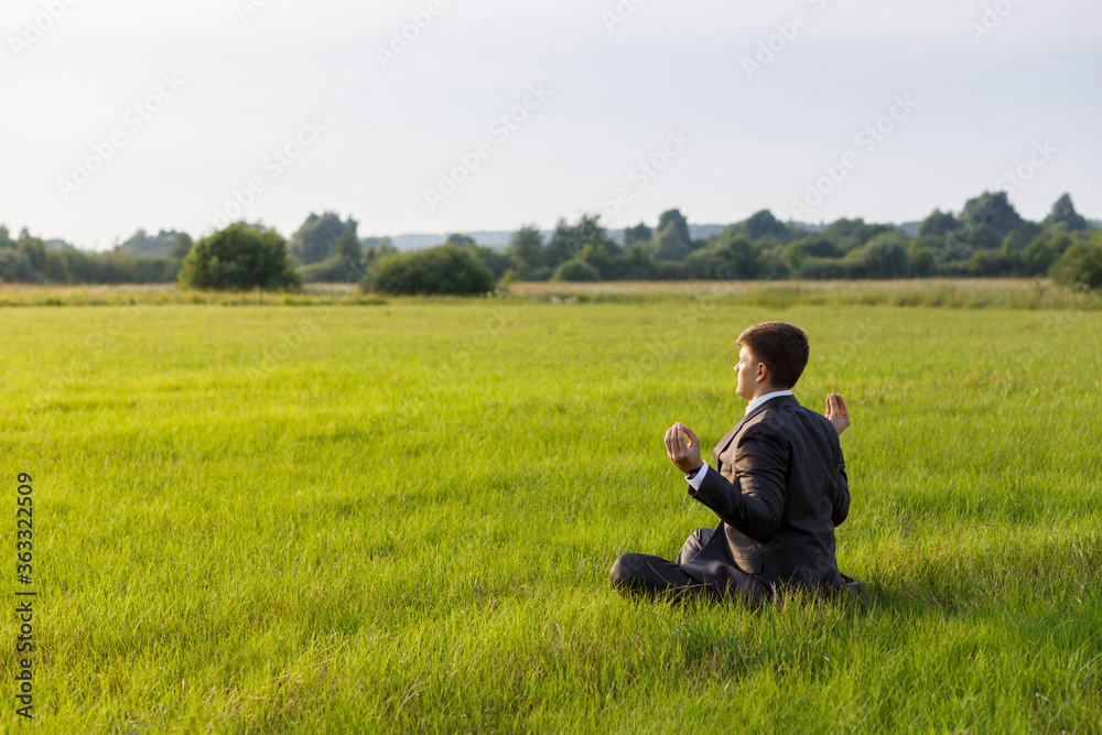 Businessman is meditating sitting on the grass in a field. Businessman is meditating sitting on the grass in a field.