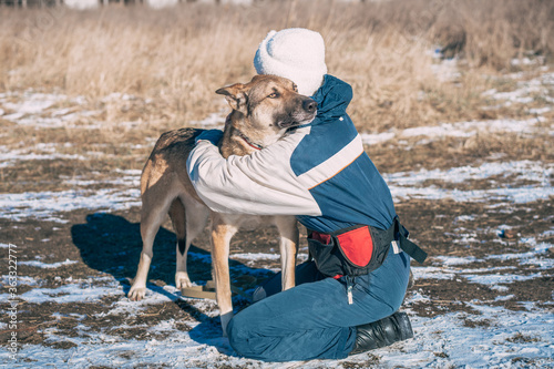 Young volunteer woman hugs scared homeless dog to make it fell safe