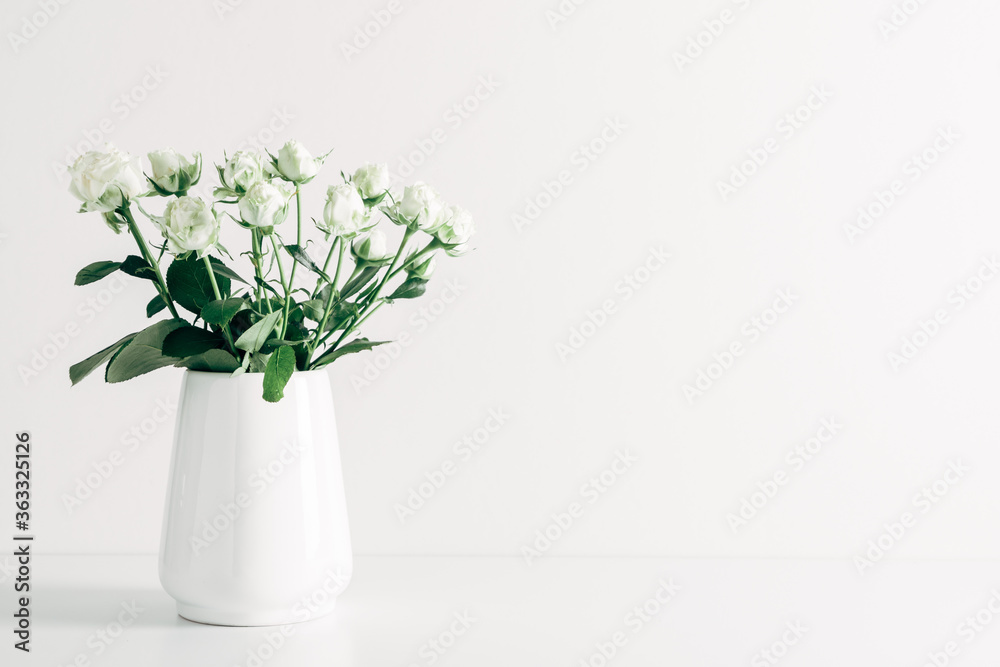 Home interior floral decor. Beautiful flowers white roses in vase on white background.