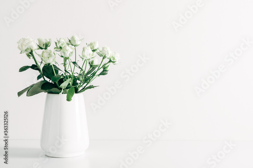 Home interior floral decor. Beautiful flowers white roses in vase on white background. © prime1001