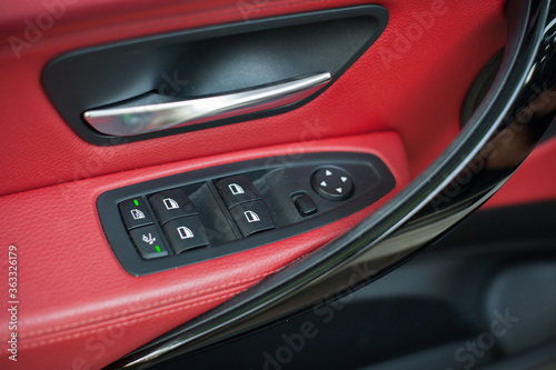 Control panel for electric windows on driver's door, detail of interior of modern car with red leather on background © Paraschiv